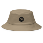 Beige bucket hat shown from a front-top angle with a black DH hex logo on the front panel