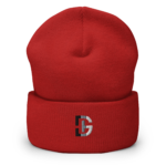 Close-up of a red knitted beanie worn on a head, showing the crown seam and a partial logo at the lower front.