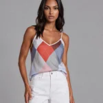 Woman wearing a pastel argyle tank top and white shorts, standing against a gray studio backdrop.